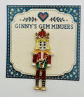 Green and red crystal nutcracker needle minder on Ginny’s Gem Minders display card