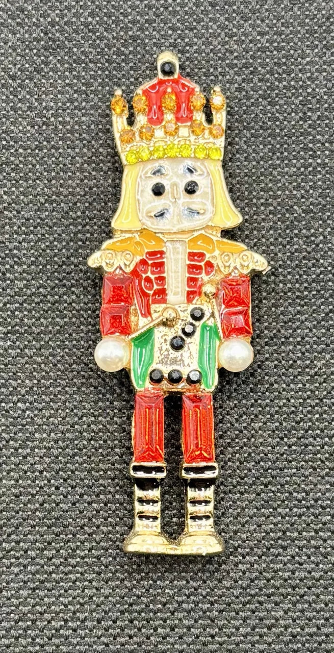 Green and red crystal nutcracker needle minder on dark fabric