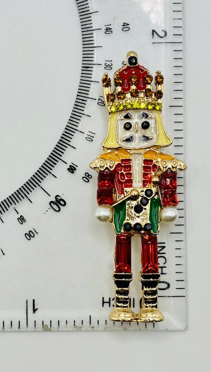 Green and red crystal nutcracker needle minder beside a ruler for scale