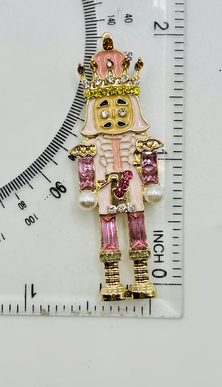 Pink crystal nutcracker needle minder beside a ruler for scale