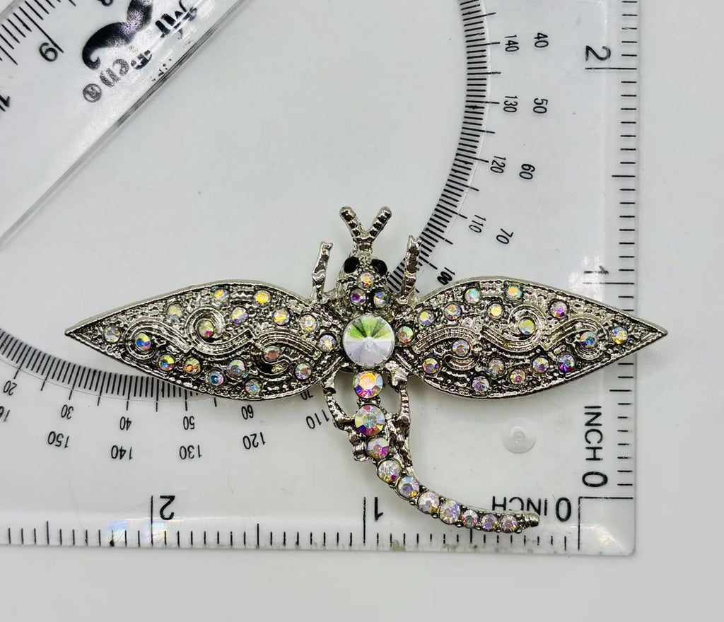 Silver and crystal dragonfly needle minder beside a ruler for scale