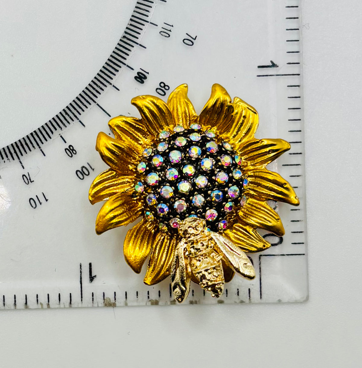 Crystal sunflower with bee needle minder beside a ruler for scale