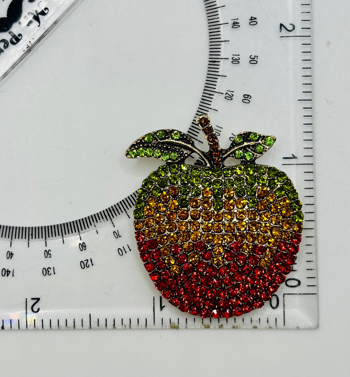 Crystal apple needle minder beside a ruler for scale