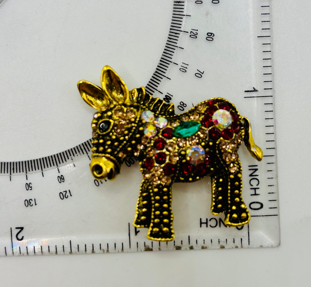 Colorful Crystal and Gold Donkey Needle Minder beside ruler for scale