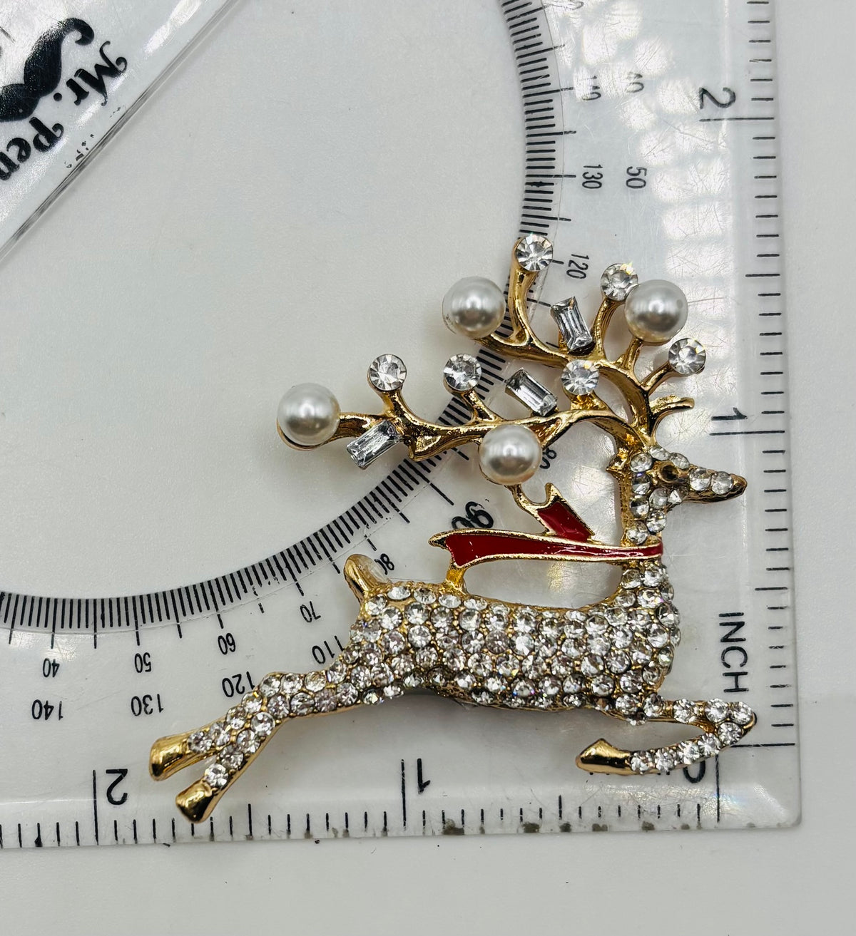 Lovely Crystal and Pearl Reindeer Needle Minder beside ruler for scale