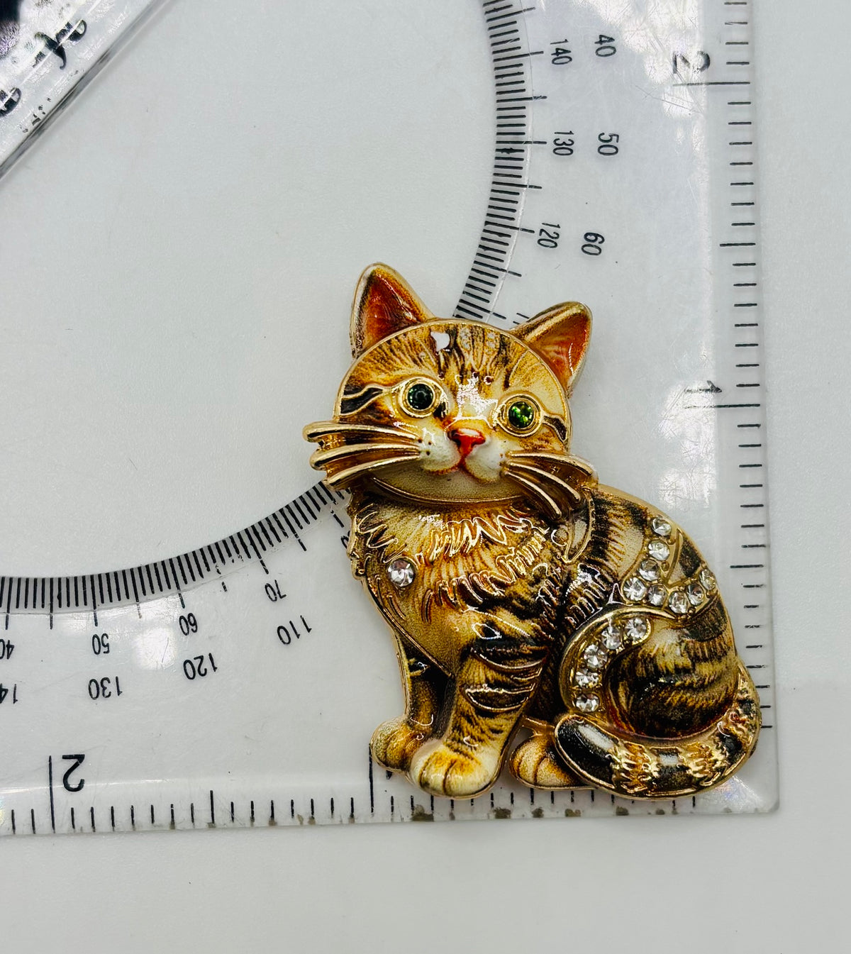Brown tabby cat kitty needle minder beside a ruler for scale