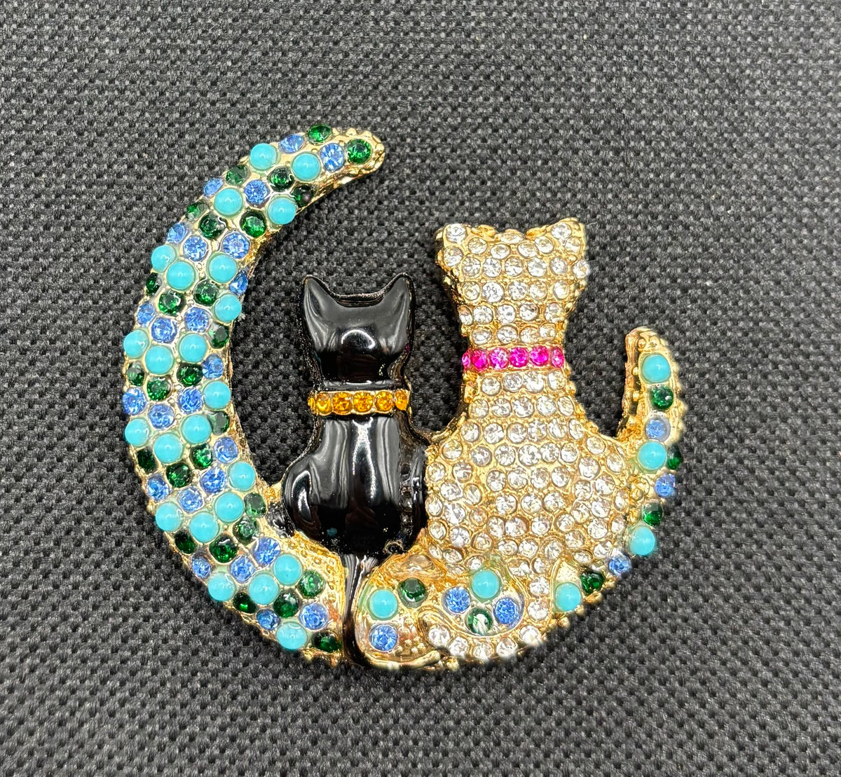 Black and crystal cats on turquoise moon needle minder on dark fabric