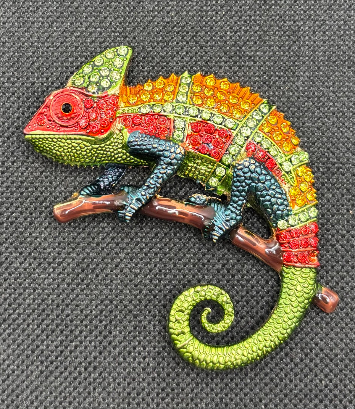 Colorful crystal chameleon needle minder on dark fabric