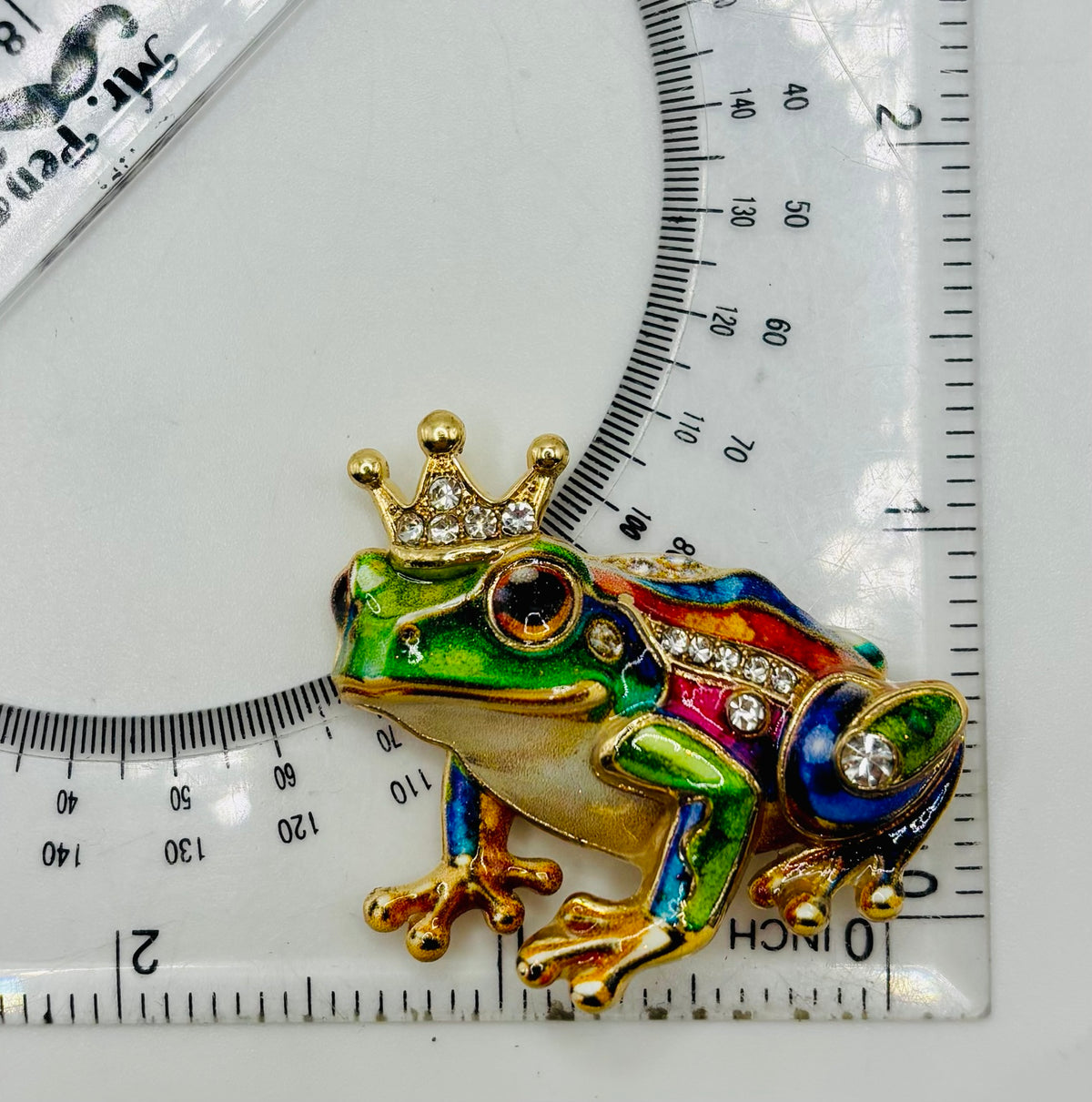 Colorful frog prince needle minder beside ruler for scale