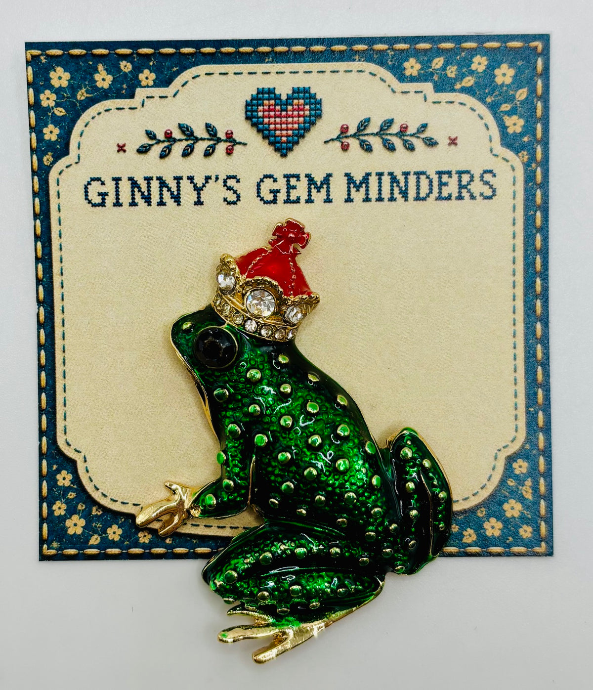 Dark green frog king needle minder on display card