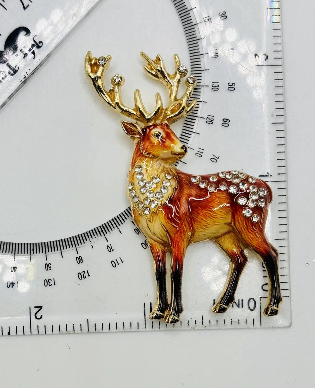 Jeweled deer needle minder beside a ruler for scale