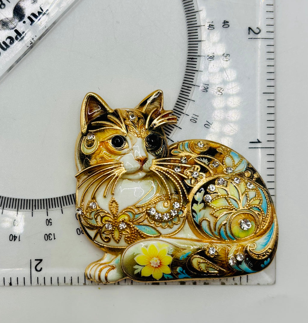 Floral crystal cat needle minder beside a ruler for scale