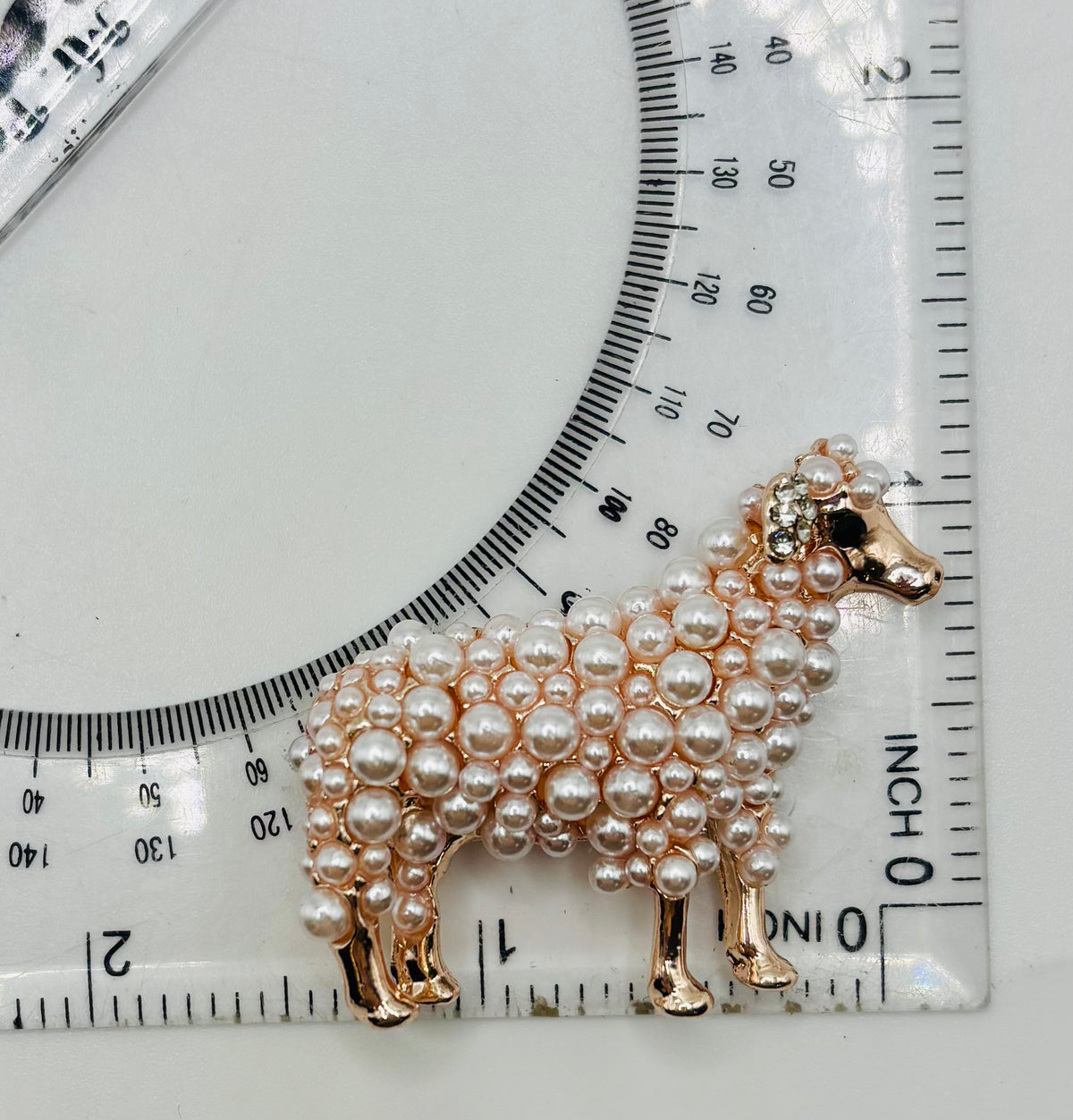 Fluffy pearl sheep needle minder beside ruler for scale