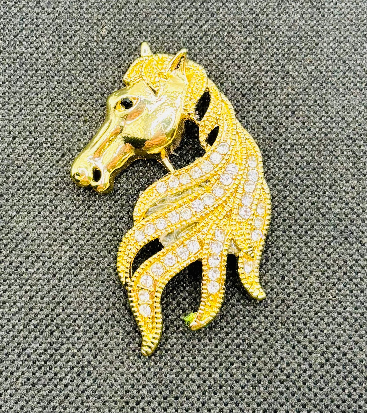 Gold and crystal horse head needle minder on dark fabric
