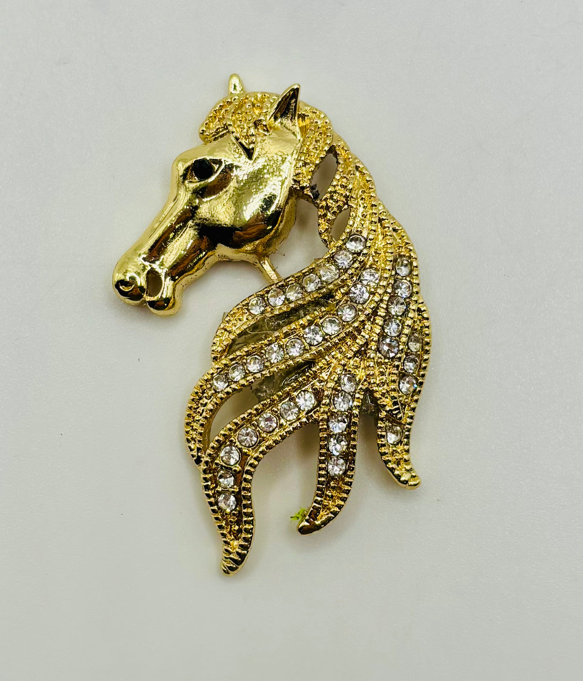 Gold and crystal horse head needle minder on white background