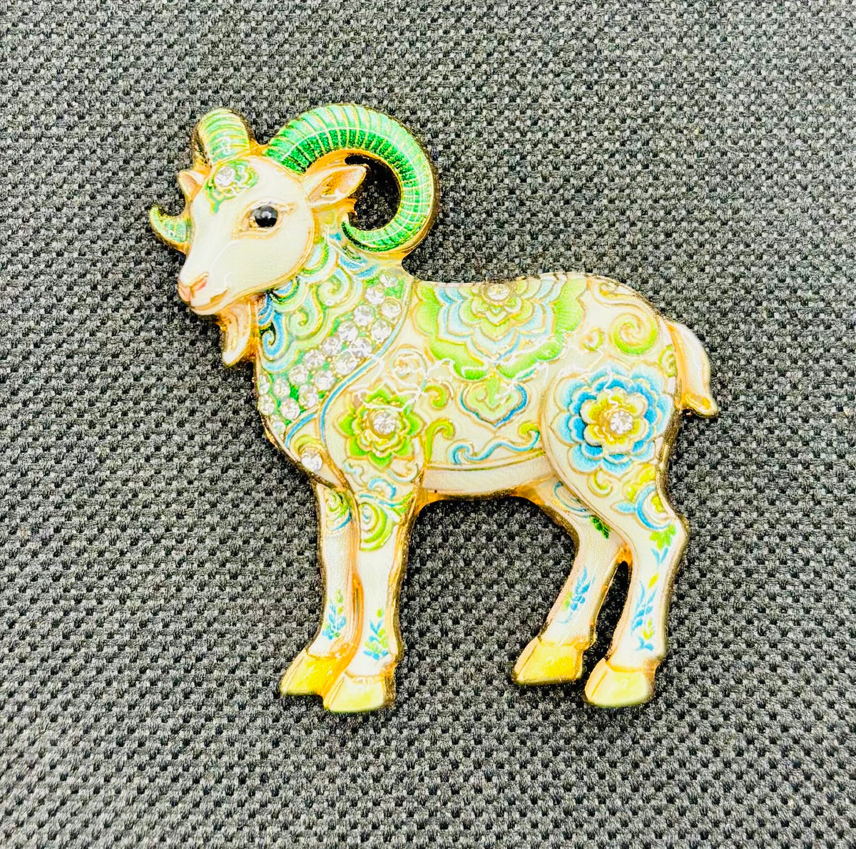 Green floral goat needle minder on dark fabric