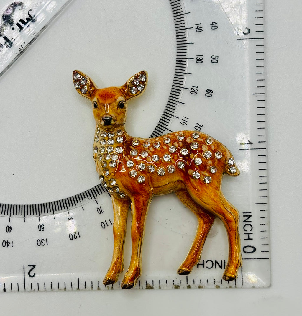 Jeweled doe deer needle minder beside ruler for scale