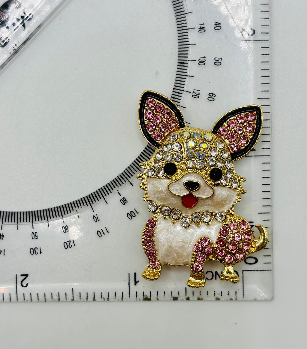 Little pink and clear crystal dog needle minder beside a ruler for scale