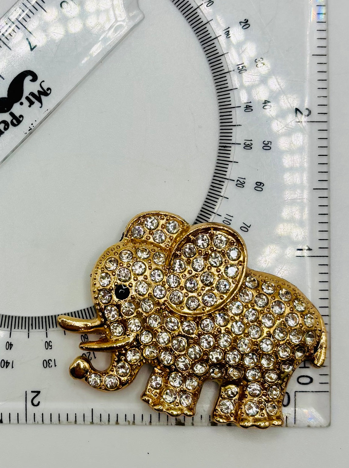 Crystal elephant needle minder beside ruler for scale
