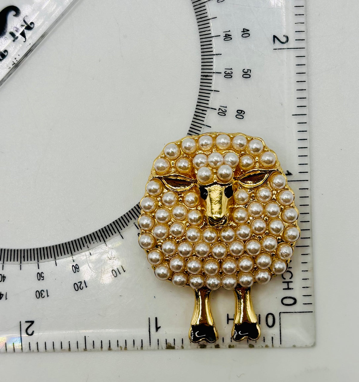 Pearl sheep needle minder beside ruler for scale