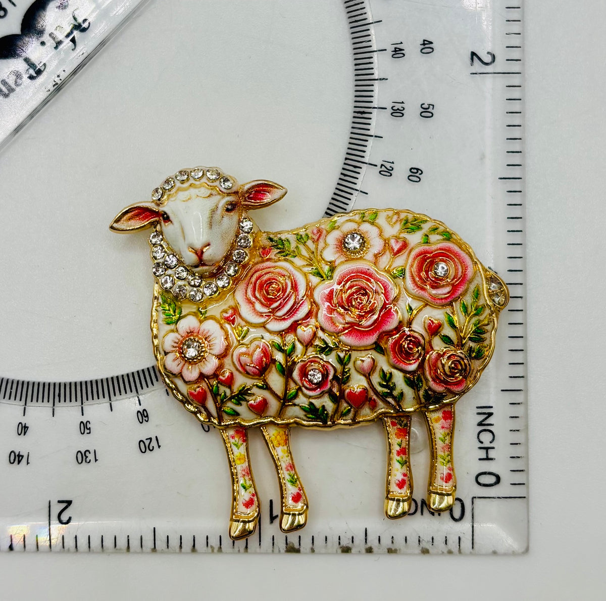 Pink flower sheep needle minder beside ruler for scale