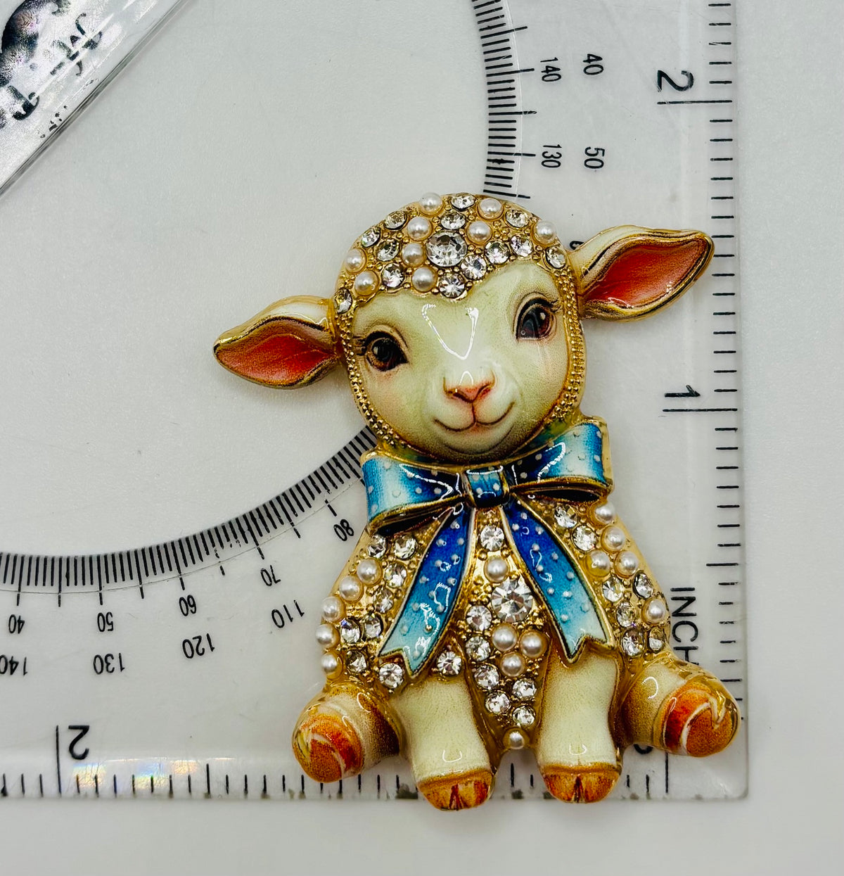 Blue bow lamb needle minder beside ruler for scale