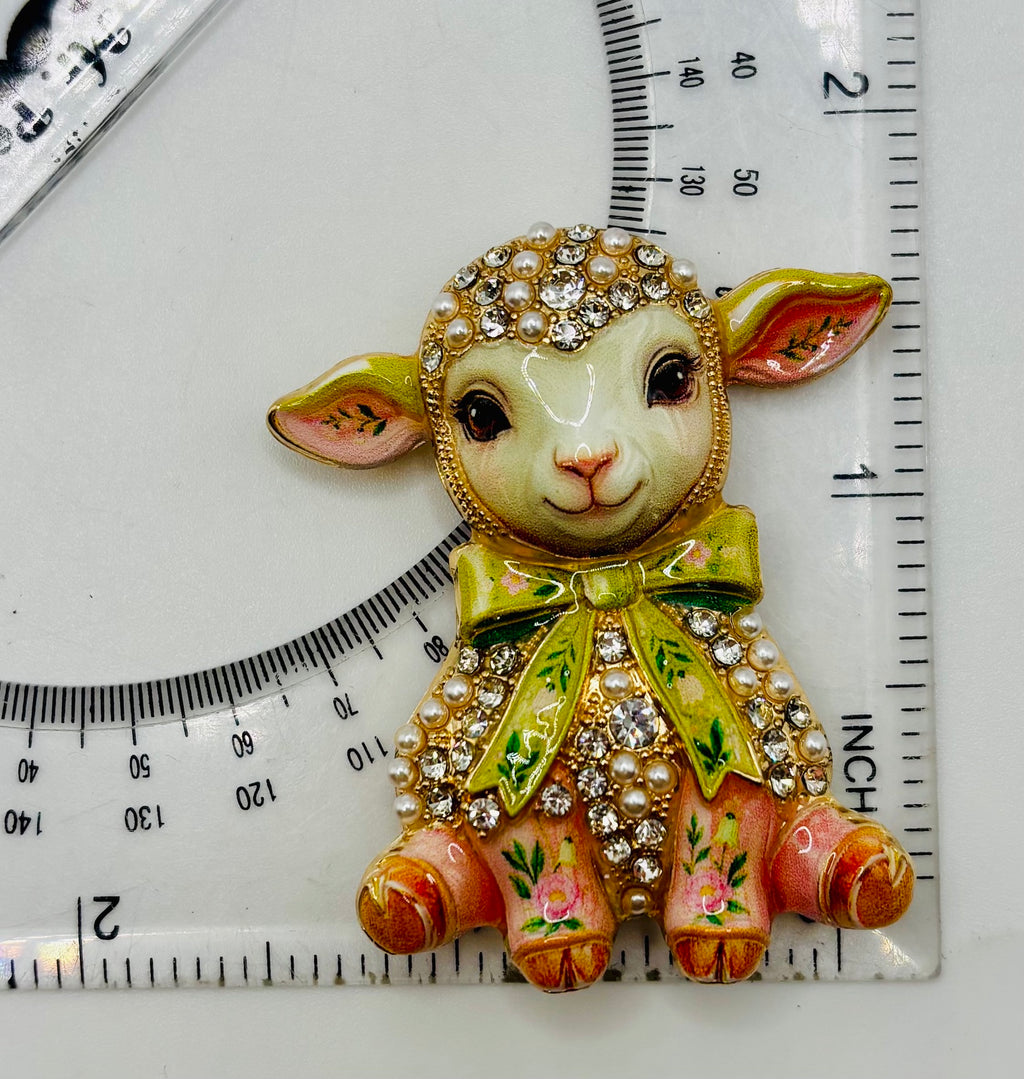 Pink lamb green bow needle minder beside ruler for scale