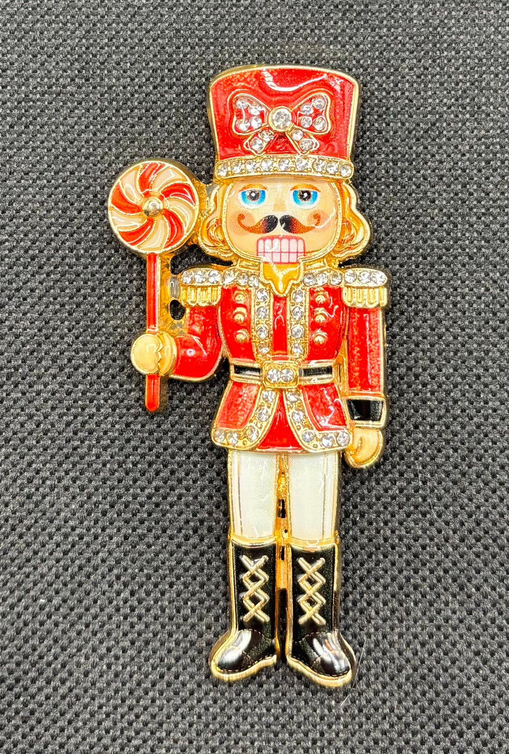 Beautiful Enamel Crystal Red Nutcracker Needle Minder on dark fabric