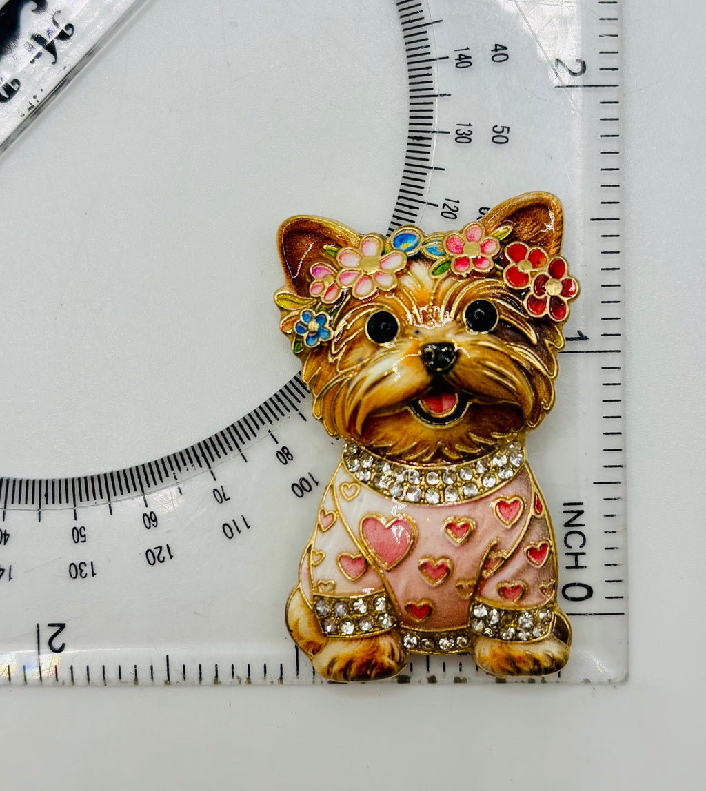 Tan dog in pink heart sweater needle minder beside a ruler for scale